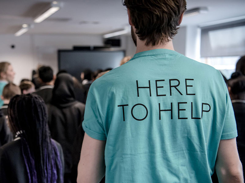 A member of London Coliseum Box Office staff wearing a 'Here to Help' t-shirt